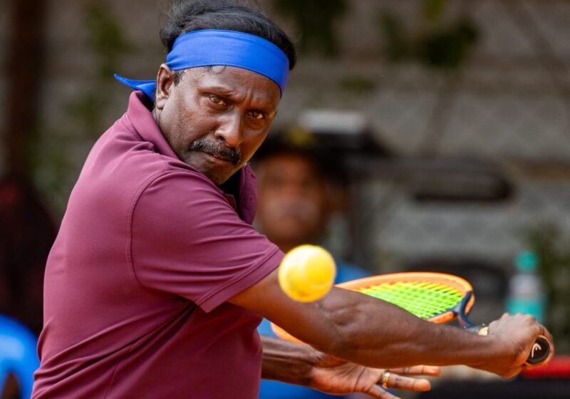 Player striking a backhand on court at True Bounce Tennis Academy, Bengaluru